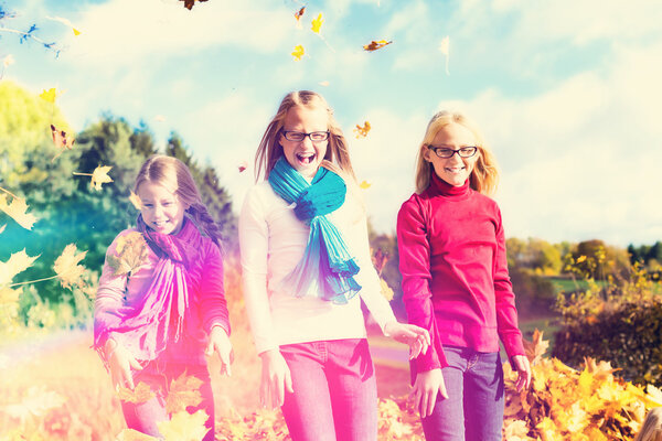 Friends romping in harvest leaves throwing foliage 