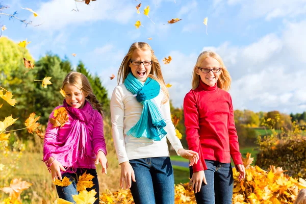 Friends romping in harvest leaves throwing foliage — Stock Photo, Image