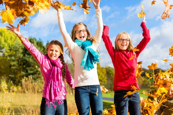Friends romping in harvest leaves throwing foliage — Stock Photo, Image