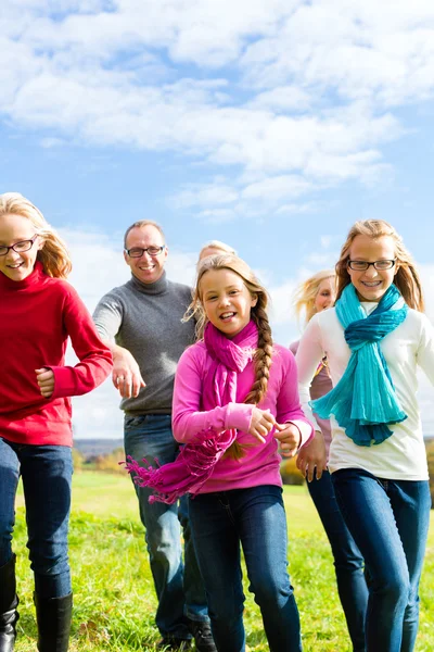 Family running through park in fall or autumn — Stock Photo, Image