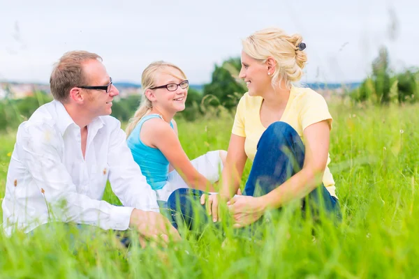 Família sentada na grama de gramado ou campo — Fotografia de Stock