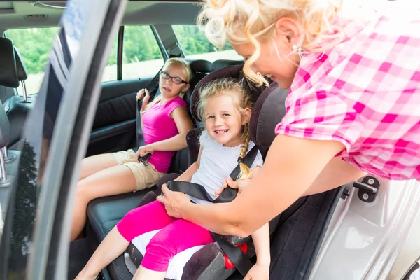 Mère bouclant sur l'enfant dans le siège de sécurité de voiture — Photo