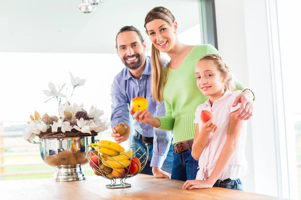 Family eating fresh fruits in kitchen — Stock Photo, Image