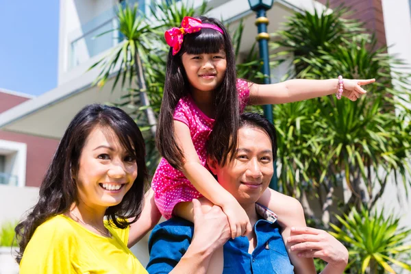 Asian family with child standing in front of home — Stock Photo, Image