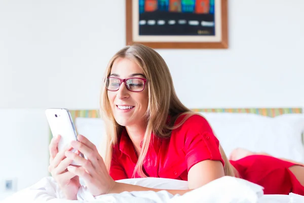 Žena, čtení e-mailů na smartphone na posteli — Stock fotografie
