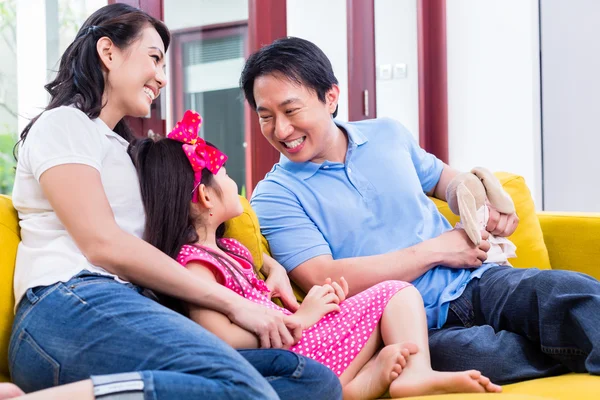 Família chinesa brincando com a filha no sofá — Fotografia de Stock