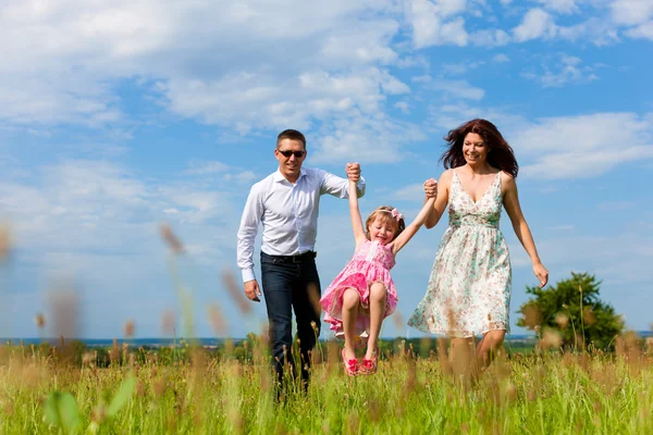 Happy family running on meadow in summer — Stock Photo, Image