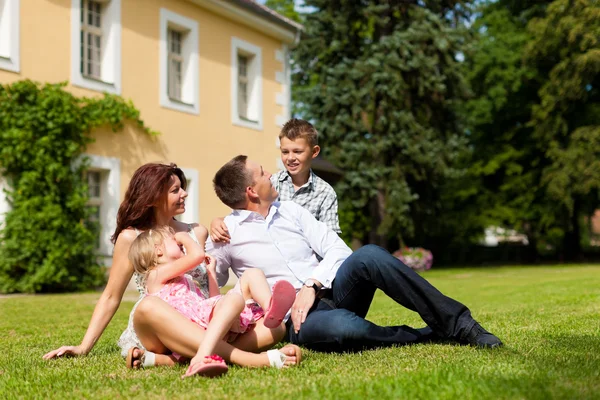 Family sitting in front of their home — Stock Photo, Image