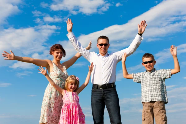 Família feliz em um prado em verão — Fotografia de Stock