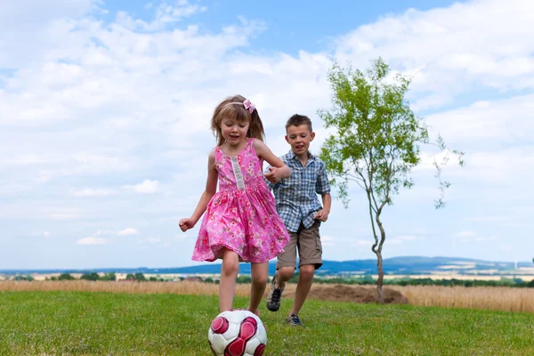 Geschwister spielen Fußball im Garten — Stockfoto