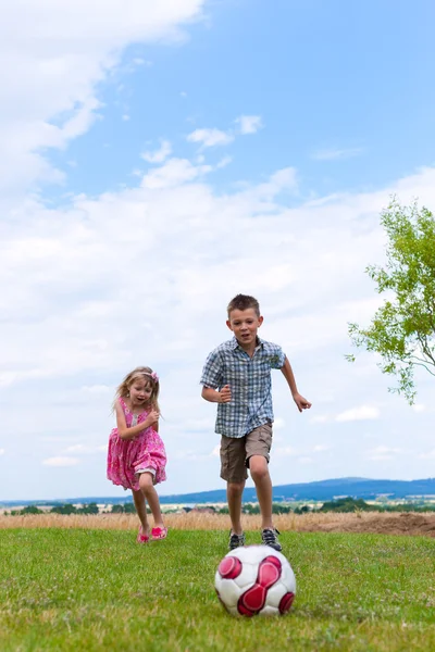 Siblings playing soccer in the garden — Stock Photo, Image