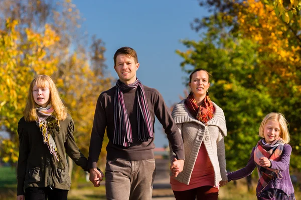 Família caminhando na frente de árvores coloridas no outono — Fotografia de Stock