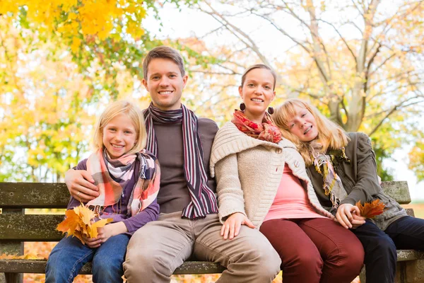 Šťastná rodina venku sedí na lavičce na podzim — Stock fotografie