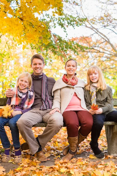 Ευτυχισμένη οικογένεια σε εξωτερικούς χώρους, κάθεται σε παγκάκι το φθινόπωρο — Φωτογραφία Αρχείου