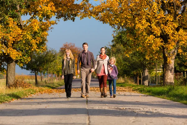 Familj med promenad framför färgglada träd i höst — Stockfoto