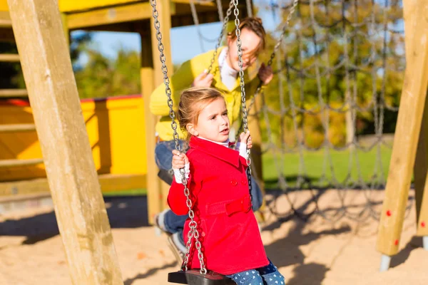 Flicka gungar på lekplats eller domstol — Stockfoto