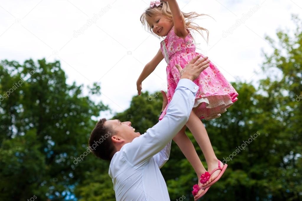 Father is playing with his daughter on a meadow