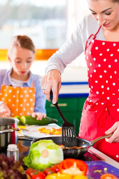 Мать учит дочь готовить дома — стоковое фото