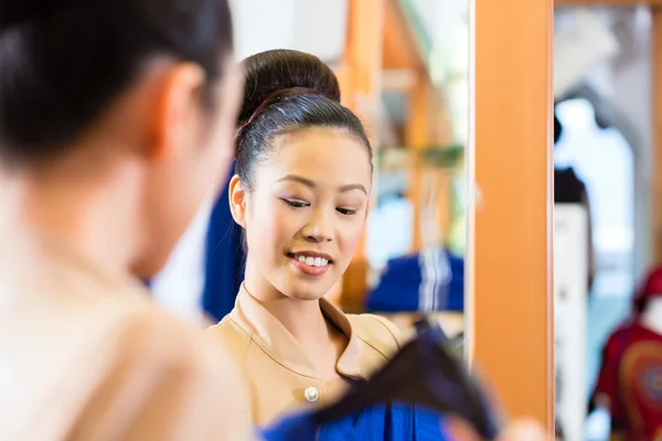 Asiática mujer tratando de ropa en tienda espejo —  Fotos de Stock