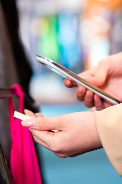 Vrouw prijsvergelijking voor kleding in winkel — Stockfoto