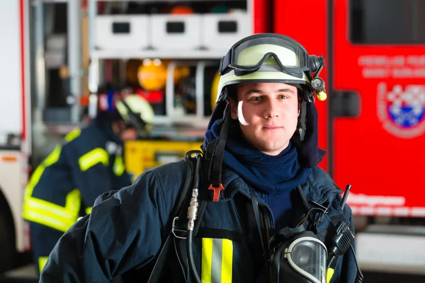 Unga brandman i uniform framför brandbil — Stockfoto