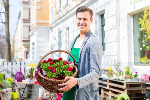 Florista com cesta de flores na loja de venda — Fotografia de Stock