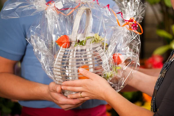 Florist in flower shop giving stuff to customer — Stock Photo, Image