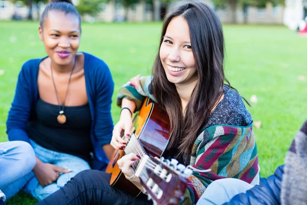 Amici che cantano canzoni nel parco divertendosi insieme — Foto Stock
