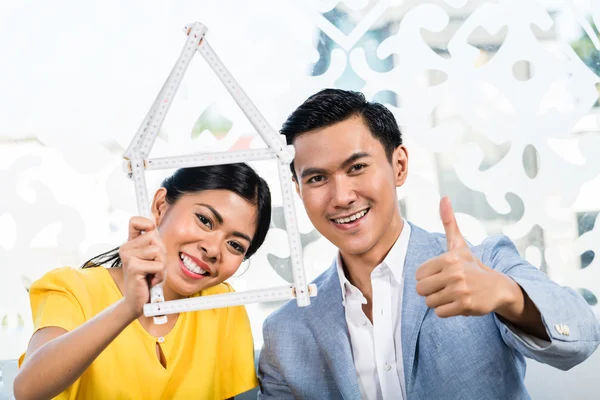 Asian couple with folding rule in furniture store — Stock Photo, Image