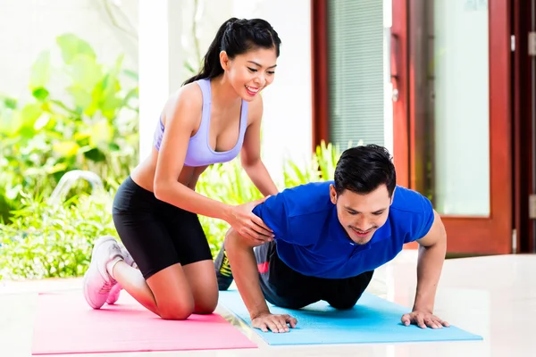 Mujer asiática ayudando a hombre con push-up — Foto de Stock