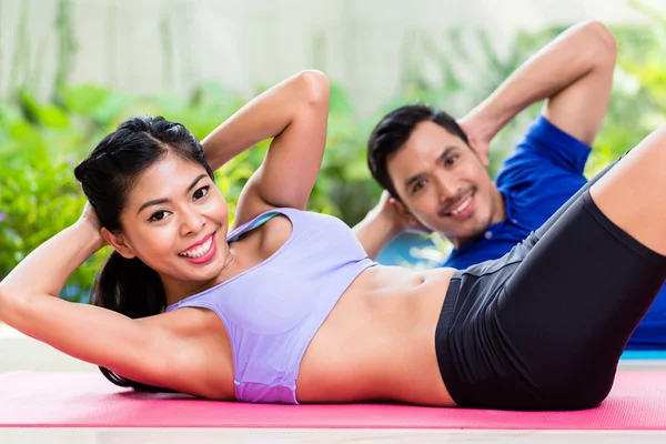 Fitness couple doing sit-up in tropical home — Stock Photo, Image