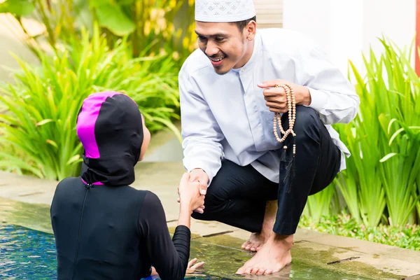 Мусульманка в бассейне приветствует своего мужа — стоковое фото