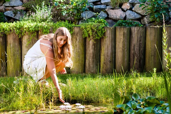 Mulher sentada na lagoa em seu jardim — Fotografia de Stock