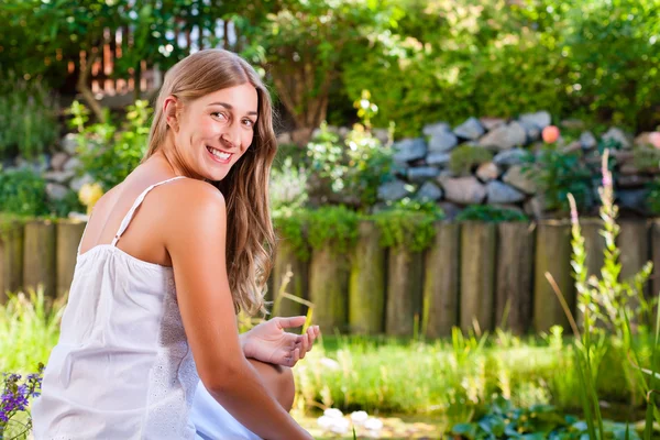 Vrouw zitten aan de vijver in haar tuin — Stockfoto