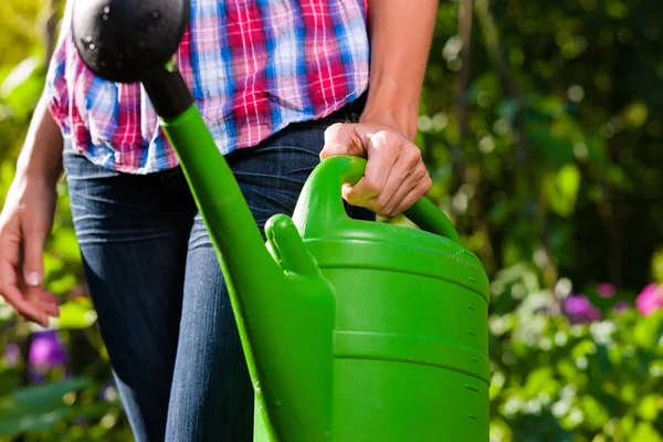 Vrouw in tuin met water kan in de hand — Stockfoto
