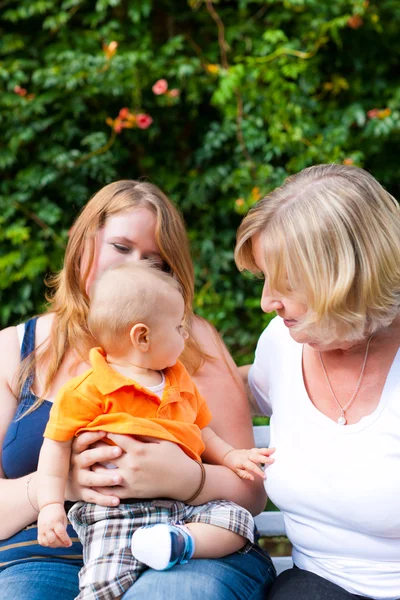 Familj - mormor, mor och barn i trädgård — Stockfoto