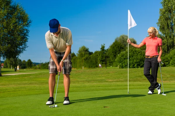 Jovem casal esportivo jogando golfe em um campo — Fotografia de Stock