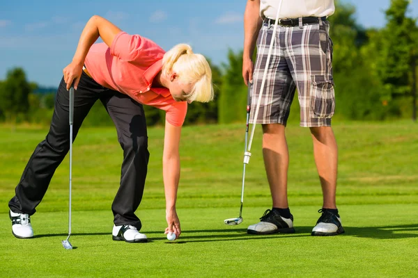 Jovem casal esportivo jogando golfe em um campo — Fotografia de Stock