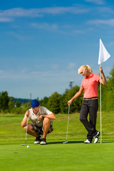 Joven pareja deportiva jugando al golf en un campo — Foto de Stock