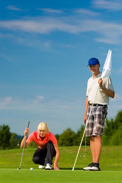 Joven pareja deportiva jugando al golf en un campo —  Fotos de Stock