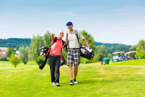 Joven pareja deportiva jugando al golf en un campo — Foto de Stock