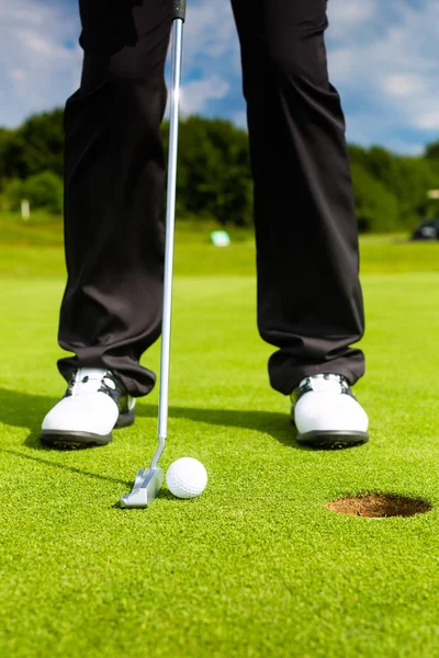 Jogador de golfe colocando bola no buraco — Fotografia de Stock