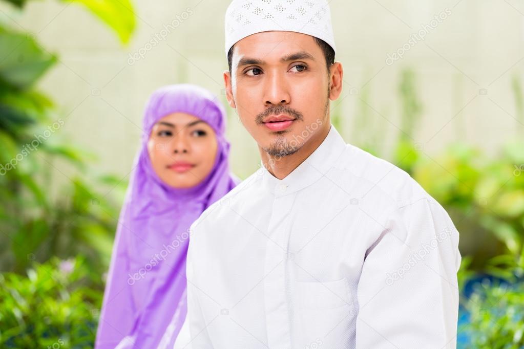 Asian Muslim couple praying at home