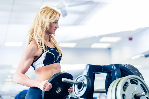 Kvinna med vikter från monter i fitness gym — Stockfoto