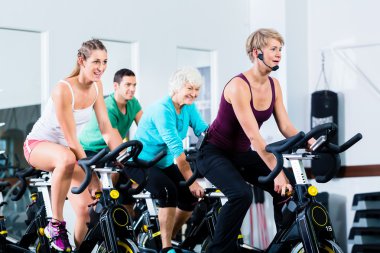 Spor salonunda fitness bisiklet üzerinde iplik üst düzey insanlar