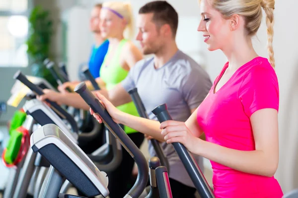 Hommes et femmes sur tapis roulant dans la salle de gym — Photo