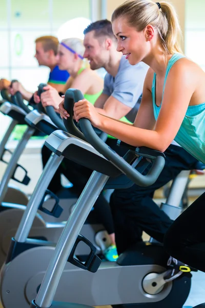 Groupe dans la salle de gym filature sur vélo de sport — Photo