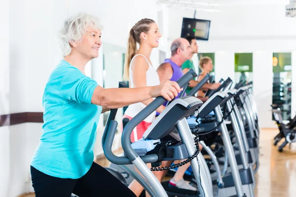 Group of people on elliptical trainer exercising in gym — Stock Photo, Image