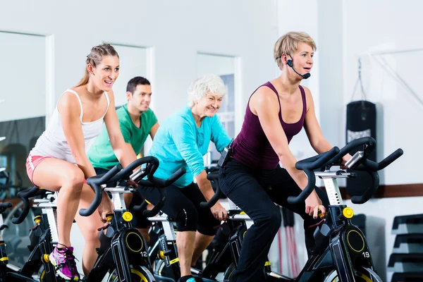 Pessoas idosas no ginásio girando em bicicleta fitness — Fotografia de Stock