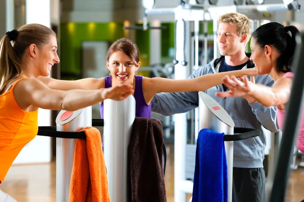Gym - les femmes et l'entraîneur avant de la machine d'exercice — Photo